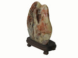 A carved decorative stone sculpture with a mountain and tree motif, displayed on a dark wooden stand against a plain white background.