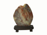 A polished decorative stone sculpture with marbled brown, cream, and gray patterns, displayed on a dark wooden stand against a plain white background.